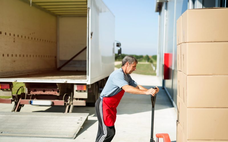 Logistics worker carrying delivered goods into warehouse